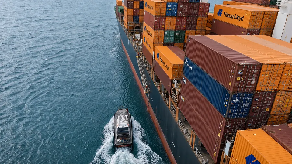 Pilot launch following a container ship during a maneuver